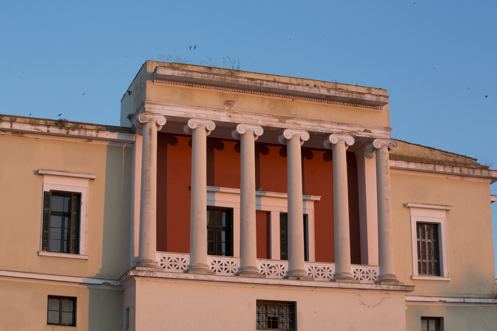 Old Courthouse Buildingwith six columns and a balcony, lit by warm sunset light against a clear blue sky.